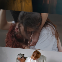 This image is divided into three parts. On the top, a blurred photo shows a group in uniform grey dresses standing in formation with their backs to the audience, arms raised overhead, while one figure stands off to the right, set apart with arms resting by her sides. In the middle, two people are embracing, with one suspended above and hanging downward, wearing a black T-shirt and jeans, while the other stands below, wearing a white T-shirt and blue jeans. On the bottom, two people wearing all-white attire kneel closely together, one partly atop the other, looking sideways, on a rectangular white drape marked with abstract multicoloured lines.