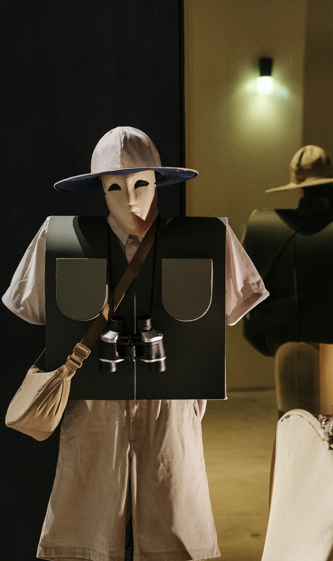 A live-installation featuring a masked bird-watcher with a pair of binoculars, and a performer wearing a large red bird costume