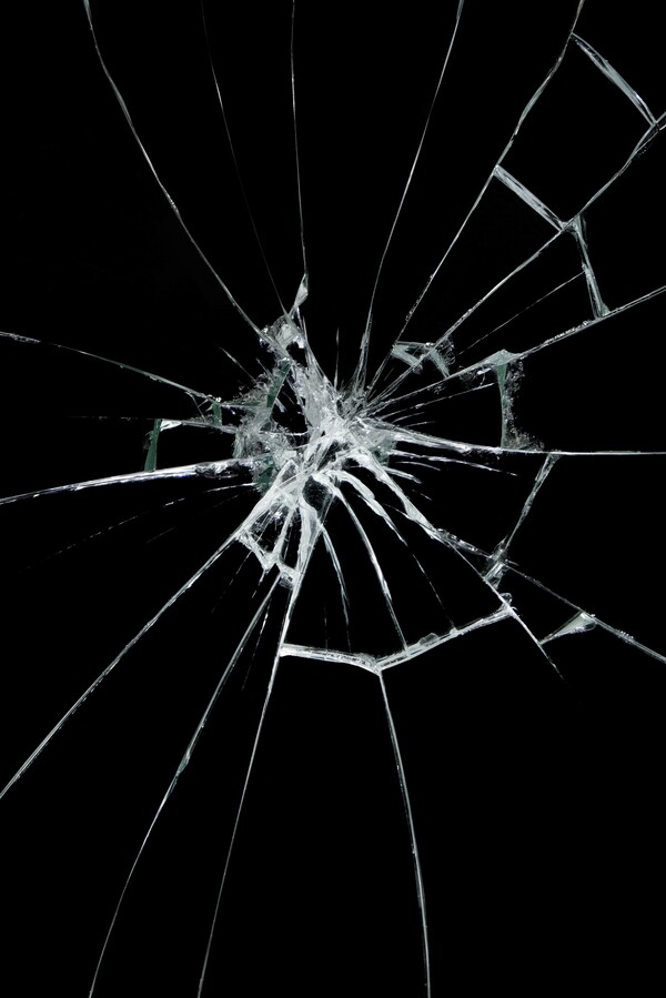 A fracture in glass set against a pitch-black background.