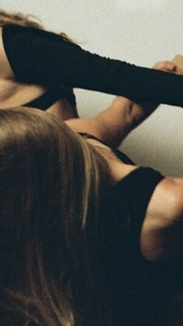 Several dancers in black outfits link arms and hands, their bodies partially visible as they lean and pull in different directions.