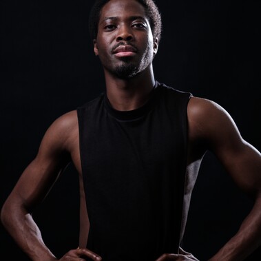 Isaac Ouro-Gnao standing in a black tank top with hands on his hips.