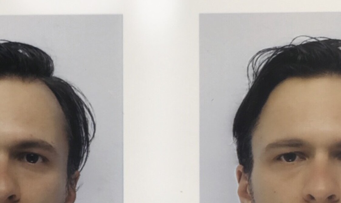 A photo booth image of a young white man cropped off centre. They are wearing a black shirt and have dark hair and eyes.