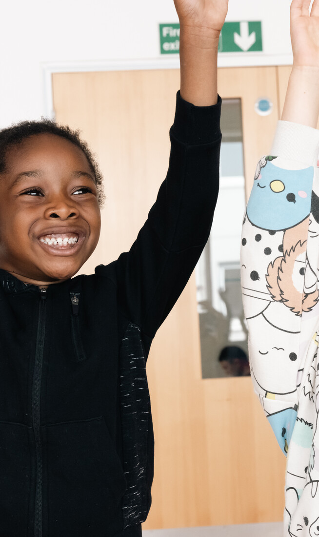 Two boys with their arms up in a dance studio.
