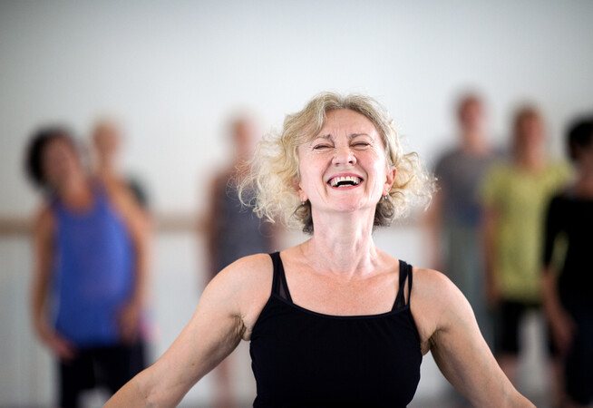 An over 60s dance class participant laughing in a dance studio