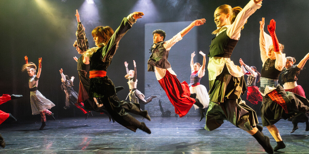 A group of young dancers leap into the air