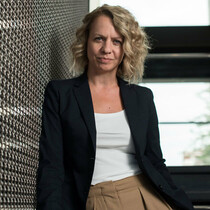 Clare Connor, Chief Executive of The Place is standing in a staircase wearing a white t-shirt and a blazer