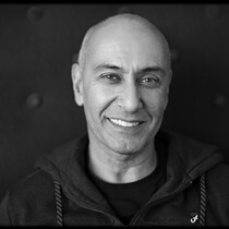 Image of Farooq Chaudhry. This image is black and white. Farooq smiles into the camera and wears a dark tracktop.