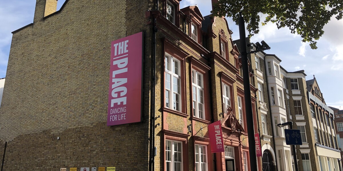 The Place building on Duke's Road from the side with a branded pink banner