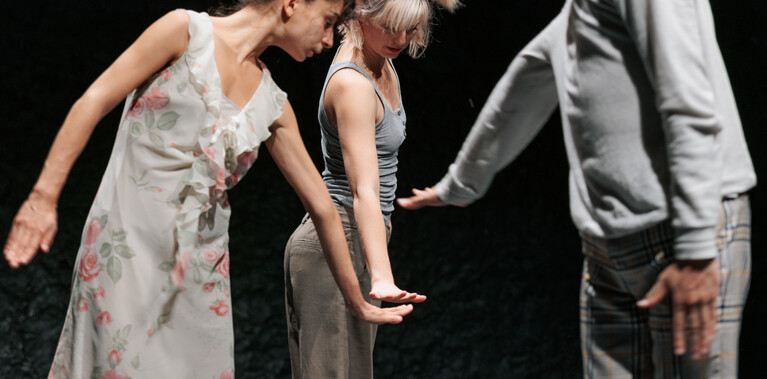 Image of three dancers dancing in front of a black background