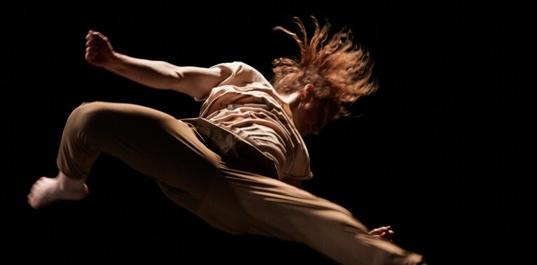 The performer, Nikki Rummer, is photographed mid-air, in the middle of an acrobatic spin.