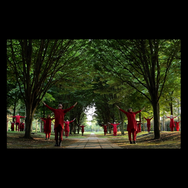 A triptych of images, the central one of a dancer amongst trees in a shimmering gold outfit, the two outer images are mirror image portraits of a fair haired little girl, thinking quizzically in vivid red.