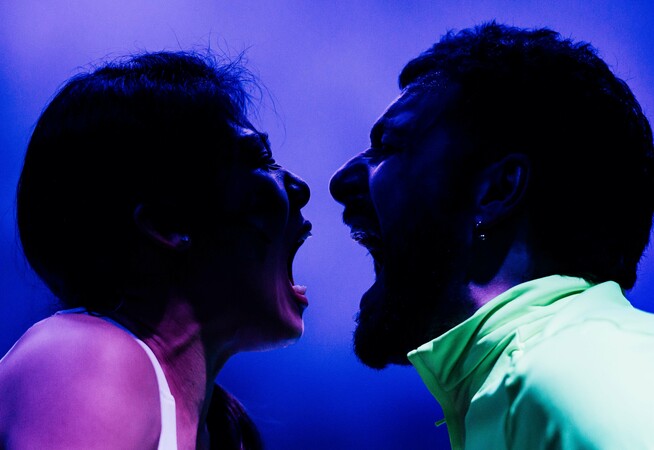 A woman and a man shouting into each others' mouths.