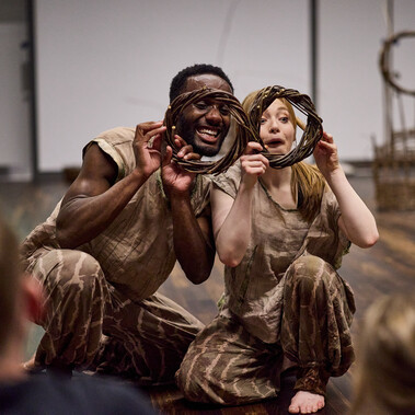 A man and woman hold willow rings in front of them and make funny faces.
